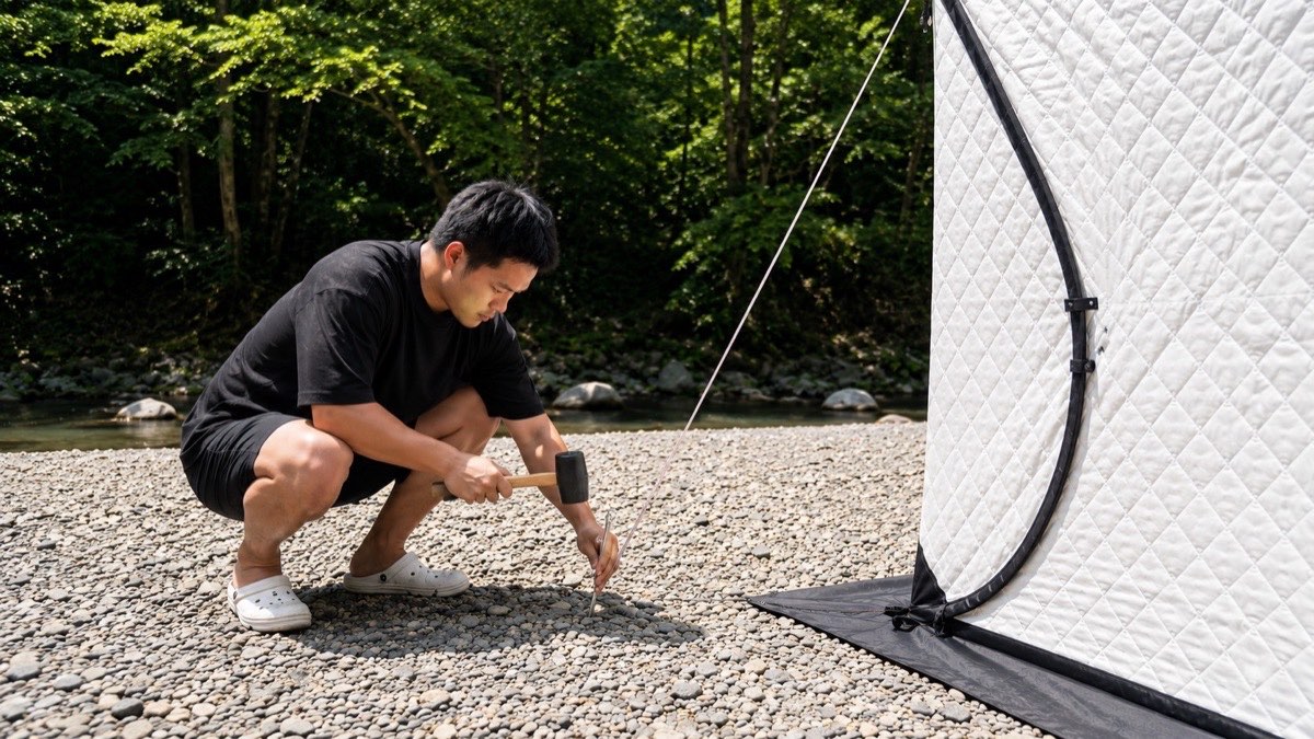 ハンマーでペグを打ち、張り綱を固定している手元